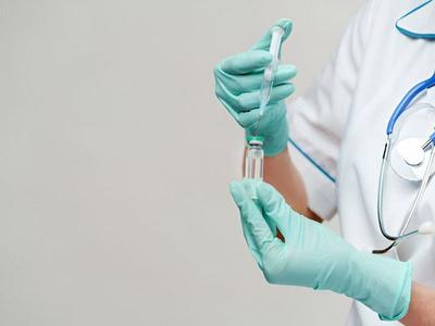 A gloved hand pipetting into a vial
